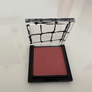 Make Up Store Blush Apricot - Säljer ett puderrouge från Make Up Store i nyansen Apricot. Färgen är en varm aprikosrosa ton som ger en naturlig och fräsch look till kinderna. Kommer i en snygg fyrkantig dosa med transparent lock och svart mönster. Perfekt för att bygga upp täckning och glow.