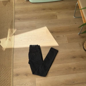 Svarta  jeans från Nudie Jeans - Säljer ett par svarta  jeans från Nudie Jeans. De har klassisk femficksdesign, smal passform och är tillverkade i mjuk bomullsdenim med stretch. Perfekta om du gillar en stilrena look i  svarta jeans. Storlek 30 32