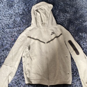 Nike tek  - Grå nike tek med svarta tender och små fickor på armen