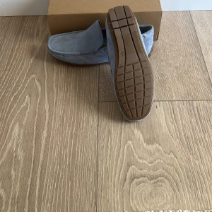 Ljusblå mockaloafers i storlek 43-44 - Snygga loafers i ljusblå mocka med klassisk design och bruna gummisulor. Skorna har diskreta metallöglor på sidorna och en stilren look.Dom är helt nya!