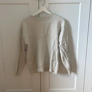 Beige/vit stickad tröja med rund hals - En stilren beige stickad tröja med rund halsringning och ribbade muddar vid ärmslut och nederkant. Perfekt för lager-på-lager och enkel att matcha med jeans eller kjol. Långärmad och i mjukt material som känns skönt mot huden. Pris kan diskuteras!