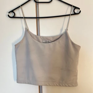croppad linnetopp Chiquelle - Säljer en stilren beige croppad linnetopp från Chiquelle. Toppen har tunna axelband och en rak, enkel passform som är perfekt till jeans eller kjol. Materialet är mjukt och lätt, vilket gör den superbekväm under varma dagar.