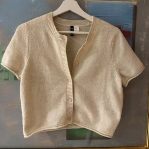 Beige kortärmad kofta från H&M - Kortärmad beige kofta från H&M! Den var aningen för kort för mig som är 174! Jag skickar gärna bild på för referens!