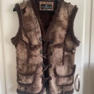 Brun pälsväst från Erik Garthus AS - Superfin brun pälsväst från Erik Garthus AS med fluffig päls på insidan och längs kanterna. Köpt på Vinted men aldrig kommit till användning!