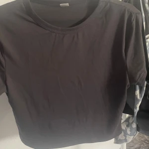 Svart basic t-shirt från SHEIN Teen - Enkel svart t-shirt från SHEIN Teen i storlek 16Y. Modellen är rak med rund halsringning och korta ärmar. T-shirten är tillverkad i mjuk bomull och passar perfekt till jeans eller shorts. Stilren och lättmatchad för en clean look.
