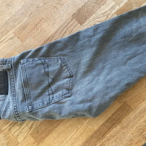 Grå slim jeans Polo Ralph Lauren 30/32 - Snygga grå jeans från Polo Ralph Lauren i modellen Sullivan Slim. Jeansen har klassisk femficksdesign, dragkedja och detaljer med Polo-logga. Slim passform och tillverkade i mjukt bomullsjeans. Perfekta för en clean och stilren look.