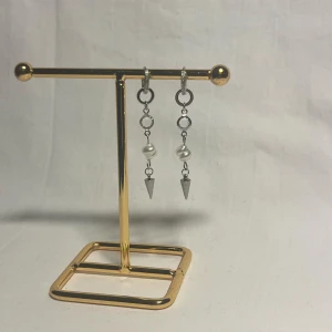 Silvriga örhängen med pärlor och spikes - Unika silvriga örhängen med små ringar, oregelbundna vita pärlor och coola konformade spikes längst ner. Ger en edgy vibe med mixen av metall och pärlor. Perfekta för dig som vill sticka ut med detaljer som syns.