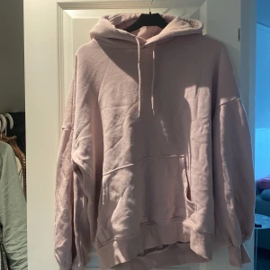 Oversized ljusrosa hoodie - Mysig oversized hoodie i ljusrosa med stor känguruficka och huva med snörning. Perfekt för chill dagar eller när du vill ha något bekvämt och snyggt. Mjuk insida och breda muddar vid ärmslut och nederkant.