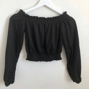 Svart offshoulder blus - Svart offshoulder blus med långa ärmar och smockdetaljer vid halsringning och midja. 
