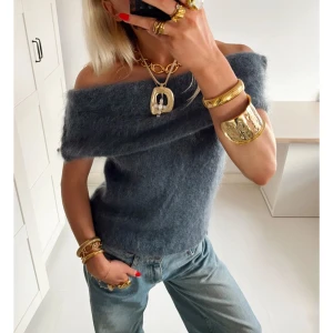 Design by si topp - Superfin mörkgrå stickad topp med offshoulder-design. Toppen är fluffig och mjuk med en bred kant som vilar snyggt över axlarna. Perfekt att styla med jeans och chunky smycken för en trendig look.