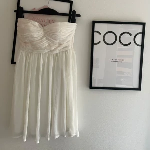 Vit axelbandslös klänning Zoul Edition - Superfin vit axelbandslös kortklänning från Zoul Edition. Klänningen har draperad överdel och ett lätt, flowy tyg i kjolen. Perfekt för sommarens alla tillfällen. Sidenliknande material som känns lyxigt och svalt. Skriv för fler bilder eller vid andra funderingar 🩷