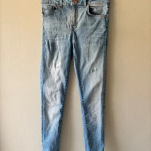 Ljusblå skinny jeans  - Jeans som är välanvända men fortfarande har mycket kvar att ge, hittade ev någon fläck (osäker om de tillhör tyget) se bild 2 och även sista bilden.  Passar någon som är mellan 157-165 skulle jag tro. Ca 33cm från sida till sida vid byxöppning.