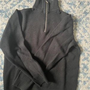 Svart stickad half zip från Jack & Jones - Svart stickad tröja från Jack & Jones med hög krage och half zip-dragkedja. Tröjan har lång ärm och är i en klassisk, enkel modell som funkar till allt. Perfekt för dig som gillar stilrena och bekväma plagg med lite edge.