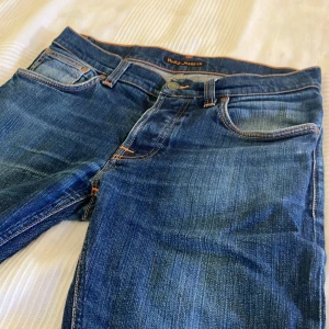 Nudie jeans grim Tim - Ett par fräscha jeans använda, men legat ett bra tag i garderoben. Lite små i storleken på midjan annars allt perfa. Passar till den stilrene människan. Midjemått:42,5cm, innerbenslängd 74 cm lårvidd 56cm