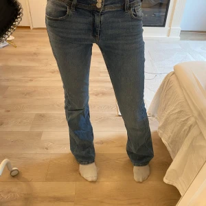 Jeans med låg midja  - Snygga blå jeans i lågmidjad modell med bootcut-ben och knappar där bak.   Lite slitna längst ner, men fortfarande i jättefint skick och helt bärbara. Perfekt till höst och vinter 🍁✨  👖 Storlek: 170 (barnstorlek) – passar även XS/S 🧵 Skick: Bra använt skick, lite slitage längst ner.   📦 Jag skickar snabbt! 💬 Skriv om du vill ha fler bilder eller hjälp med styling 💸 Pris kan alltid diskuteras!