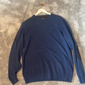 Mörkblå stickad tröja från Barbour - Snygg mörkblå stickad tröja från Barbour i storlek M. Tröjan har rund halsringning, långa ärmar och coola mockadetaljer på armbågarna. Broderad Barbour-logga framtill. Perfekt för dig som gillar klassisk men stilren look.