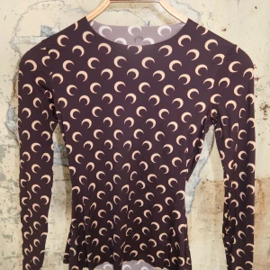 Marine Serre tröja  - Nypris 2100kr. Snygg brun långärmad topp med beige månmönster över hela plagget. Tight passform och rund halsringning. Perfekt för dig som gillar unika prints och vill sticka ut lite extra. Materialet känns stretchigt och följsamt.