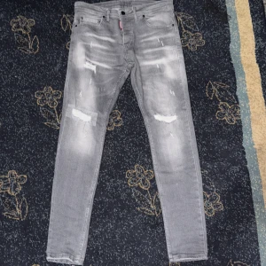 Grå jeans från Dsquared2 - Snygga grå jeans från Dsquared2 med slitna detaljer och tvättad look. Klassisk femficksmodell med låg midja och stretchig bomullskvalitet. Perfekta för dig som gillar streetstyle och vill sticka ut med en cool vibe.