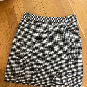 Rutig kjol från Nicci Hernestig NA-KD - Supersnygg svartvit rutig minikjol från Nicci Hernestig x NA-KD. Kjolen har klassiskt rutmönster, hög midja och bälteshällor. Perfekt för dig som gillar en preppy och trendig stil.
