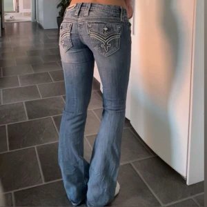 Rock Revival blå bootcut jeans - Snygga blå jeans från Rock Revival med bootcut passform. Revorna är design och måtten är midja:35cm innerben:78cm! Passar nån som är runt 1.63! skriv för fårgor och bilder!  Tryck gärna köp nu! 
