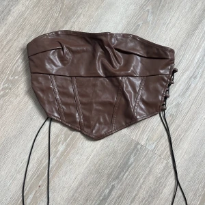 Brun skinnkorsett med snörning -  en brun korsettopp i skinnimitation med snörning på sidorna