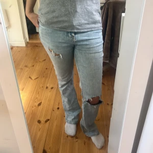   bootcut jeans med hål - Säljer ett par ljusblå bootcut jeans. Jeansen har snygga slitningar vid knä och lår, klassisk femficksmodell och låg/mid rise 
