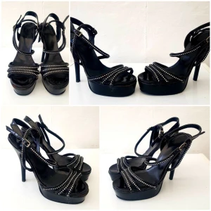 Svarta platåpumps med nitar och klack - Snygga svarta pumps med hög klack och platåsula. Skorna har flera smala remmar dekorerade med små silverfärgade nitar och spänne vid ankeln. Öppen tå och lackad finish ger en edgy vibe. Perfekta för dig som vill sticka ut. Står att det är storlek UK 6 vilket motsvarar 39. Jag själv har storleken mellan 37 & 38. Så tycker den är mindre egentligen. Jag har ganska breda fötter så klackarna ser aningen smala ut på mig. 