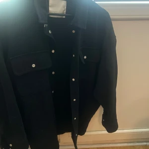 Svart overshirt/jeansjacka från Co'couture - Svart overshirt/jeansjacka från Co'couture. Köpt på Nelly för flera år sedan va för ca 2000kr. Storlek M oversized. Finns ett bälte till att knyta i midjan. Aldrig använd 