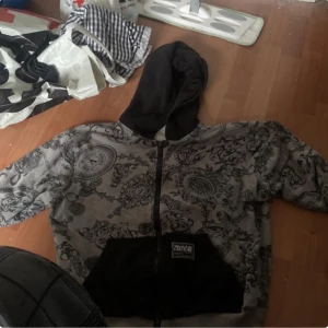 Grå hoodie från Versace Jeans Couture - Säljer en grå och svart hoodie från Versace Jeans. Den kostade 4400 ny ser att den är äkta på logorna och tvättlappen..