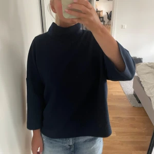 Mörkblå polotröja Carin Wester - Snygg mörkblå polotröja från Carin Wester med hög krage och avslappnad passform. Tröjan har trekvartsärmar och är tillverkad i ett mjukt material som känns skönt mot huden. Perfekt att styla med jeans eller kjol för en clean look.