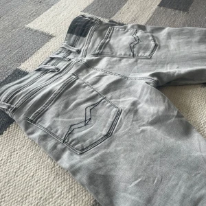 Replay Anbass grå slim jeans herr - Snygga grå jeans från Replay, modell Anbass. Slim fit med klassiska fem fickor och coola detaljer på bakfickorna. Jeansen har en stilren look. De är sparsamt använda och är i bra skick. Storlek W32 L34🔥🔥🔥