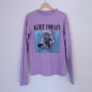 Bandtröja - PULL&BEAR strl XS - Pastell-lila Kurt Cobain tröja från PULL&BEAR strl XS lite stretchig, har några små defekter (se sista bilden)  Mått - längd 69cm, bredd 46cm, armlängd från axel 62cm. Är tyvärr för tajt på mig. Kan fixa fler bilder samt mått vid intresse! 