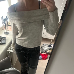 Ljusgrå offshoulder stickad tröja - Säljer en ljusgrå stickad tröja med bred offshoulder-krage. Tröjan är mjuk och har långa ärmar, perfekt för lager-på-lager och en avslappnad stil.