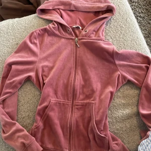 Rosa velour hoodie med dragkedja från  Cubus - Mysig rosa hoodie i velour med huva och dragkedja framtill. Tröjan har långa ärmar, ribbade muddar och två fickor framtill. Perfekt för en avslappnad stil.