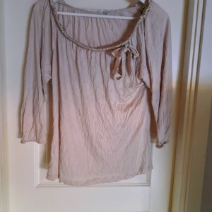Beige blus med rosett och trekvartsärm - Säljer en beige blus med trekvartsärm och dekorativ rosett vid halsringningen. Blusen har en lös passform och är tillverkad i ett lätt, syntetiskt material. Perfekt för dig som gillar en enkel men söt stil. Lappar är bortklippta. Den är Lagad på insidan vid söm. Det syns inte tycker jag. Den passar storlek s. Jag minns inte vilket märke den är Men den är i alla fall inte från temu, shein eller liknande 