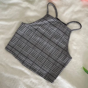 Rutig croppad linnetopp - Säljer en croppad linnetopp med smala axelband och svartvitt rutigt mönster. Toppen har en rak passform och är perfekt för varma dagar. Materialet känns mjukt och stretchigt.