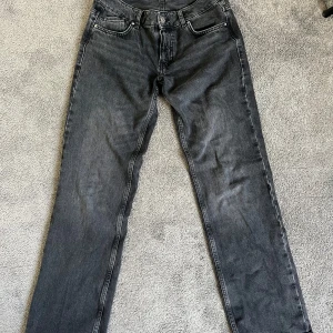 Svarta raka jeans från Zara - Snygga svarta jeans från Zara med rak passform och klassisk femficksdesign. Jeansen har låg midja och stängs med knapp och dragkedja. Perfekta till vardags för en stilren look.