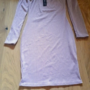 Ljuslila off shoulder ribbad klänning från NLY One - Säljer en ljuslila ribbad klänning från NLY One i modellen Off Shoulder Rib Dress. Mauve. Klänningen har smala ränder, lång ärm och en figurnära passform. Perfekt för dig som gillar en stilren och trendig look. Oanvänd 
