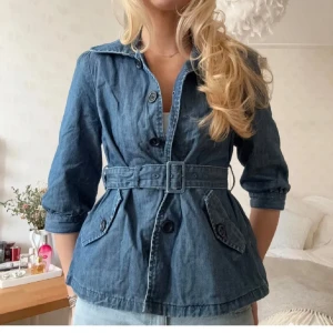 Jeansjacka med knytning - Snygg jeansjacka med trekvartsärm i blå denim med markerad midja tack vare ett matchande bälte. Köpt på plick men säljer pga för stor för mig (lånade bilder)