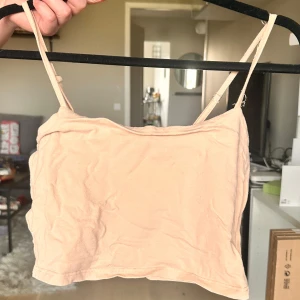 Beige croppad linnetopp - Säljer en enkel och stilren beige croppad linnetopp med tunna axelband. Perfekt att matcha med jeans eller kjol för en avslappnad look. Toppens material känns mjukt och lätt mot huden.