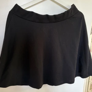 Svart kjol från FB Sister - Enkel svart kortkjol från FB Sister. Kjolen har en lätt utsvängd form och bred linning. Perfekt att matcha med en crop top eller hoodie för en chill look. Lite nopprig men i övrigt inga defekter.