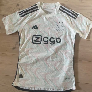 Ajax vit bortatröja 2022/23 från Adidas storlek S - Säljer denna ajax tröja i storlek S. Lite av trycket på stjärnorna över loggan är borta men annars som sprillans ny då den knappt är använd 