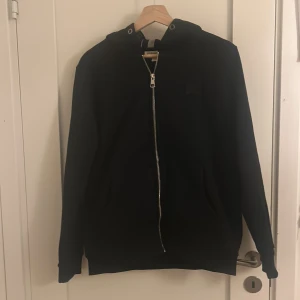 Burberry zip hoodie - Hej, säljer denna Zip hoodie ifrån burberry. Hoodien är i nytt skick och använd ett fåtal gånger med inga defekter eller liknade, lite problem med dragkedjan. Top kvalitet för ett väldigt bra pris som ej är hugget i sten vid snabb affär🙂