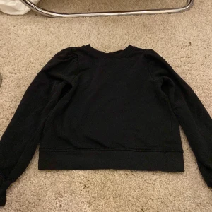 Svart tröja från KappAhl - En enkel svart långärmad tröja från KappAhl i storlek XS. Tröjan har rund halsringning och är tillverkad i ett mjukt material som passar perfekt till vardags. Stilren och lätt att matcha med andra plagg.