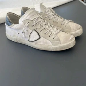 Philippe Model - Snygga vita sneakers från Philippe Model med svarta detaljer och snörning. Skorna har en rund tå och en unik design med mönstrad häl. Perfekta för en stilren look.(Storlek 41) (Är smutsiga i designen)