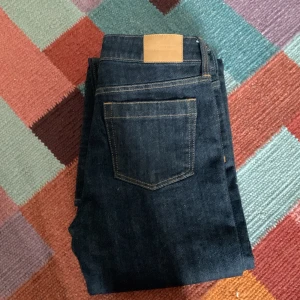 Mörkblå jeansbyxor från Weekday - Snygga mörkblå jeansbyxor med klassisk femficksdesign och kontrastsömmar. Byxorna har en rak passform och en stilren look som passar till många olika outfits. Perfekta för dig som gillar en tidlös stil. Inga defekter, aldrig använda. Ställ gärna frågor, prisförslag eller någonting annat!