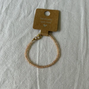 Pärlarmband med guldfärgat lås - Säljer ett handgjort armband med små pech färgade pärlor och ett guldfärgat klolås. Perfekt accessoar för att ge en söt och stilren touch till din outfit. Armbandet är enkelt men ändå elegant och passar till många olika stilar.💕