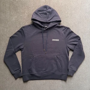 Mörkblå hoodie från Jacquemus och raffe skjorta  - Snygg mörkblå hoodie från Jacquemus med justerbar huva och ribbade muddar. Perfekt för en avslappnad stil. Diskret logga på bröstet ger en stilren touch. Modellen är 174 och väger 58 kg. Skriv för fler frågor.