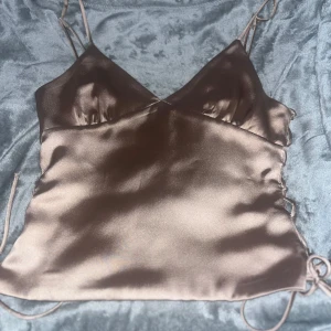 Champagnefärgad satinlinnetopp med snörning - Säljer en champagnefärgad linne-topp köpte den här på Plick men den var för liten vill bysten för mig som C kupa så skulle jag säga att den skulle passa någon med mindre.Den har inga defekter eller något sånt.🥲💕