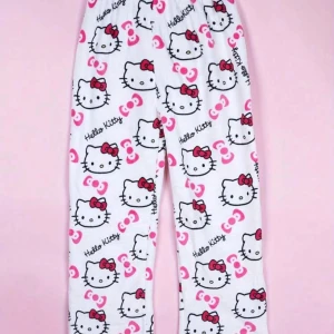 Vita fleecebyxor med Hello Kitty-mönster - Supermjuka och mysiga vita fleecebyxor med Hello Kitty-tryck i rosa och svart. Byxorna har elastisk midja och är perfekta för hemmamys eller som pyjamasbyxor. Söt design med röda rosetter och Hello Kitty-ansikten över hela tyget. HAR FLERA STORLEKAR. HELT NYTT!